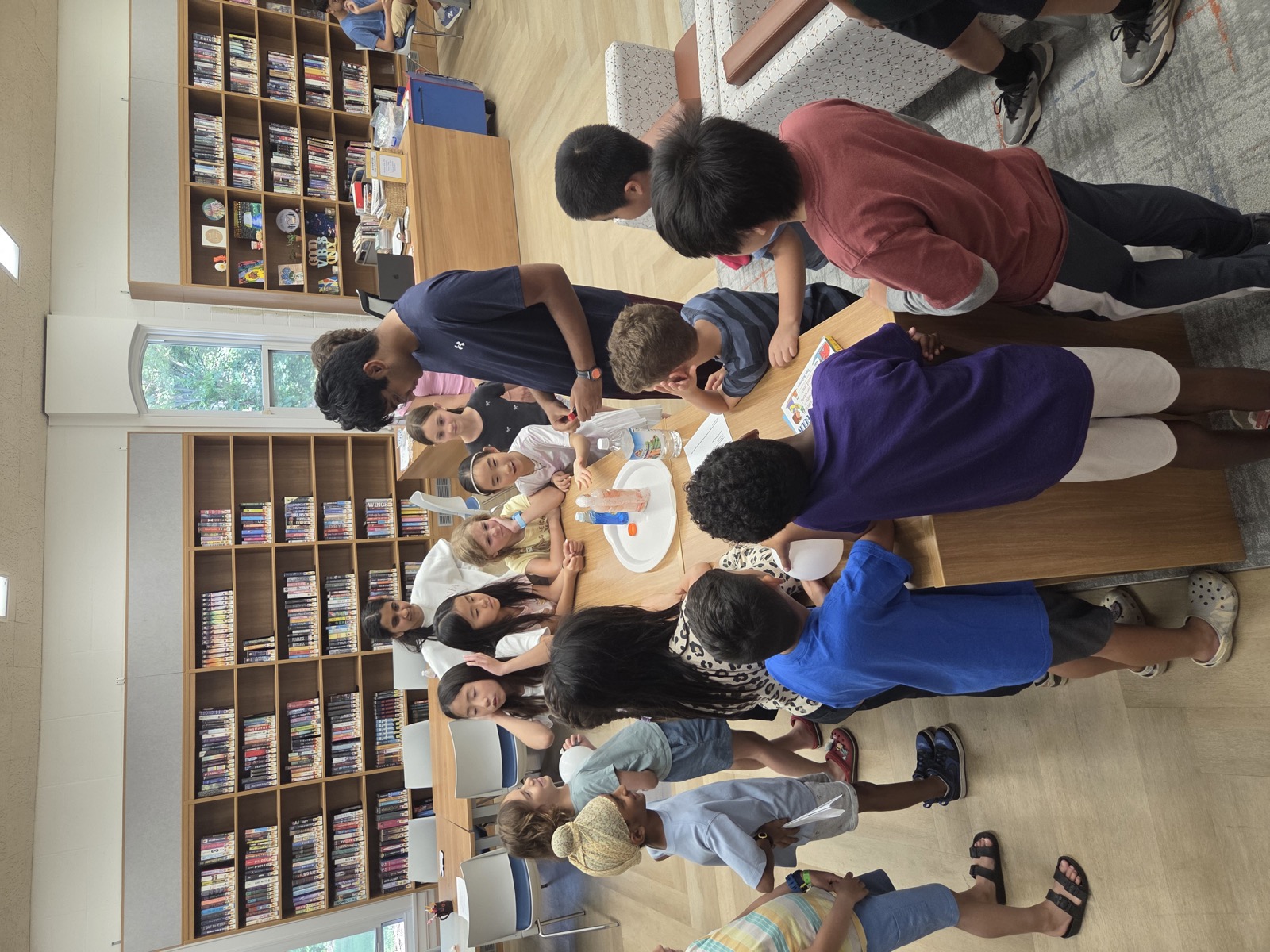 Students gathered around a table watching an erupting volcano experiment